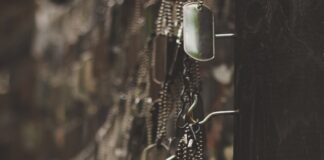 silver-colored god tags hanging on hooks shallow focus photography