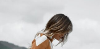 woman in white short shorts looking on rocks while putting her hand in pocket