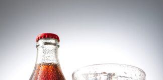 coca cola bottle beside drinking glass