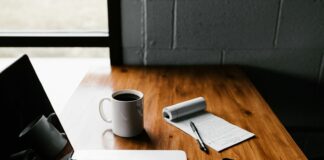 MacBook Pro, white ceramic mug,and black smartphone on table