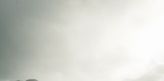 black train on railway bridge under heavy clouds