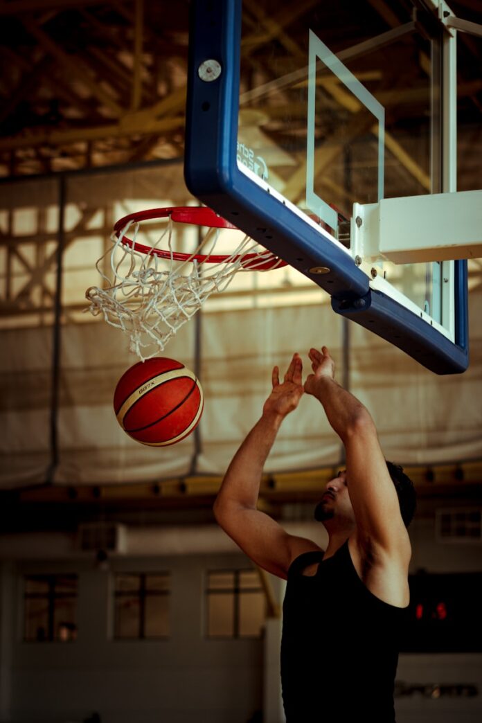 A man dunking a basketball in a gym