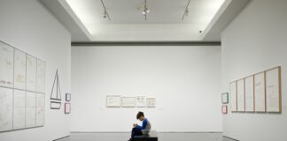man sitting near museum painting