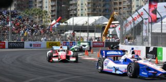 a group of racing cars driving down a race track