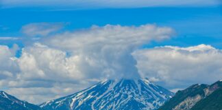 a snow covered mountain sitting above a lake
