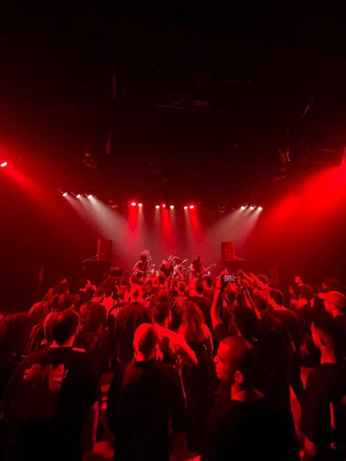A crowd of people in a dark room with red lights
