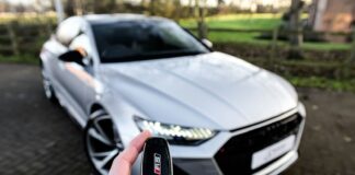 a person holding a car key in front of a silver car