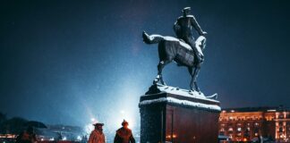 two person walking near person riding horse statue