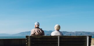 man and woman sitting on bench facing sea