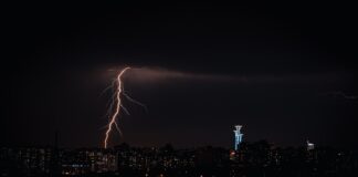a city skyline at night with lightning striking the ground