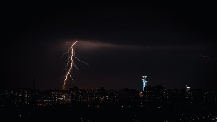 a city skyline at night with lightning striking the ground