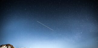 photo of shooting star over snow covered mountains