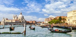 white and brown boat on water near white concrete building during daytime