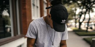 person in black adidas cap sitting on bench writing on notebook