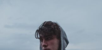 man in black and red hoodie standing on gray concrete pavement during daytime