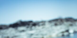 a hand holding a cigarette in front of a body of water