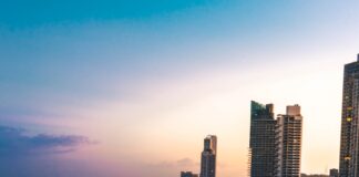 high rise buildings near body of water in distant of mountain