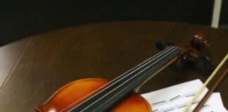 a violin sitting on top of sheet music next to a cup of coffee