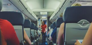 flight attendant standing between passenger seat