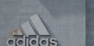 man standing in front of boy leaning on adidas building wall