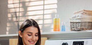 a woman is holding a basket near a washing machine