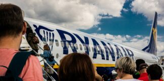people sitting on chair near blue and white airplane under white clouds during daytime