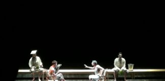 Actors perform a scene on a theater stage.