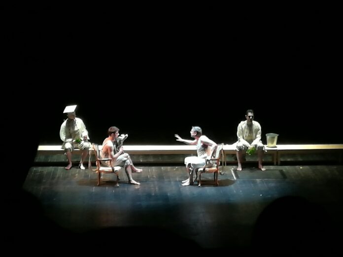 Actors perform a scene on a theater stage.