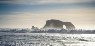 a large body of water with a rock in the background