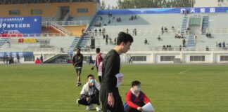man in black and white long sleeve shirt and black pants sitting on green grass field