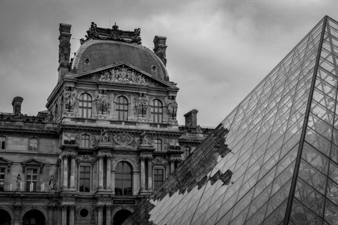 a black and white photo of a building and a glass pyramid