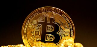 a bitcoin sitting on top of a pile of gold nuggets