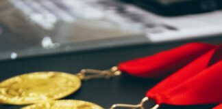 a row of gold medals with a red ribbon
