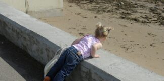 a little girl laying on a concrete ledge
