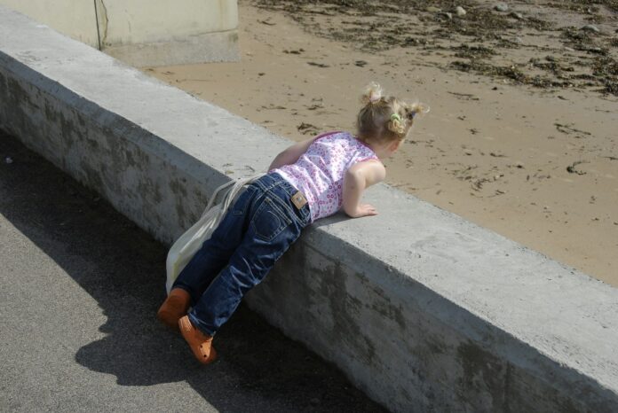 a little girl laying on a concrete ledge