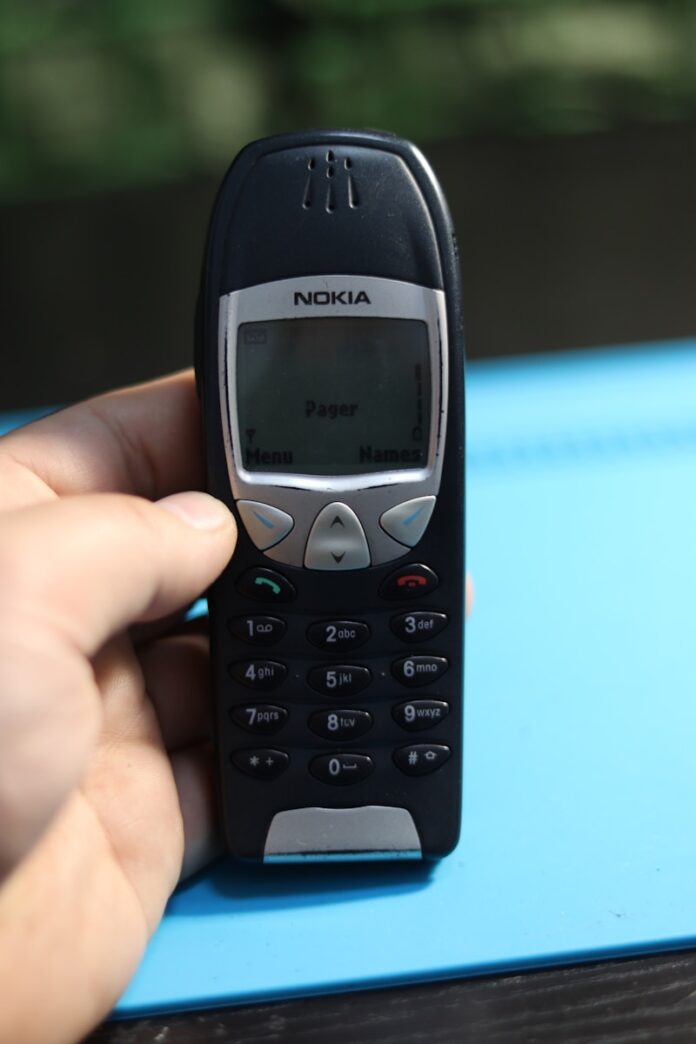 A hand holds a classic nokia phone.