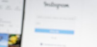 A person holding a smart phone with social media on the screen