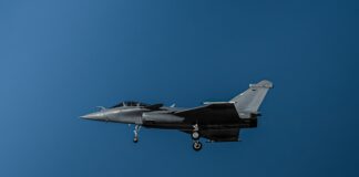 a fighter jet flying through a blue sky