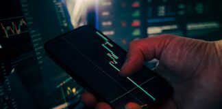 Trader analyzing stock market data on smartphone and phone