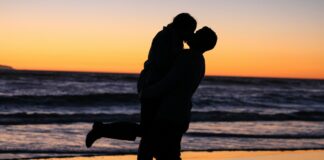 silhouette photo of couple kissing near sea during golden hour
