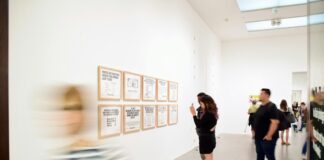 three men and woman standing while looking at bulletin board