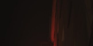 Vertical neon sign spelling "teatr" at night.