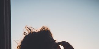 man holding forehead under sunset