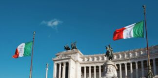 white concrete building with red flag on top under blue sky during daytime