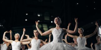 group of ballerinas dancing while raising both hands