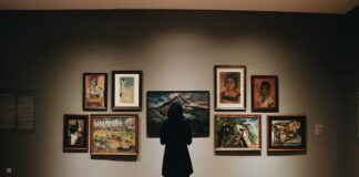 woman in black coat standing in front of paintings