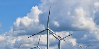 white wind turbines on green grass field under blue and white cloudy sky during daytime