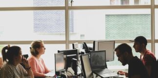 woman in pink shirt sitting in front of black laptop computer