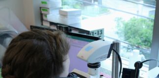 a woman in a lab looking through a microscope