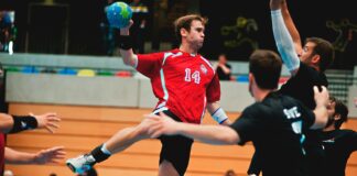 man holding ball while jumping near three mne